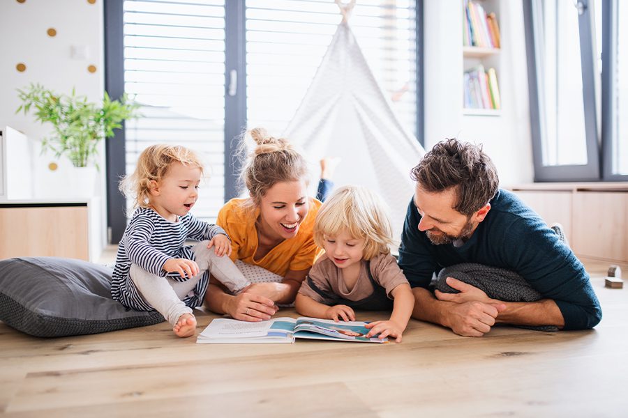 Blog - Young Family with Two Small Children Indoors in the Living Room Reading a Book