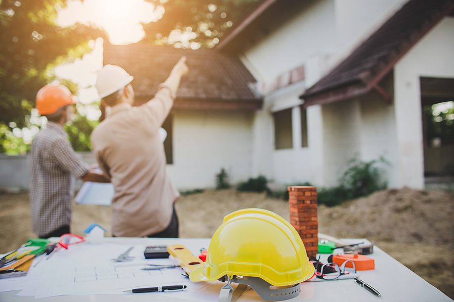 Specialized Business Insurance - Engineer Pointing and Inspecting the Workplace for an Architectural Plan with Sun Showing Through the Trees
